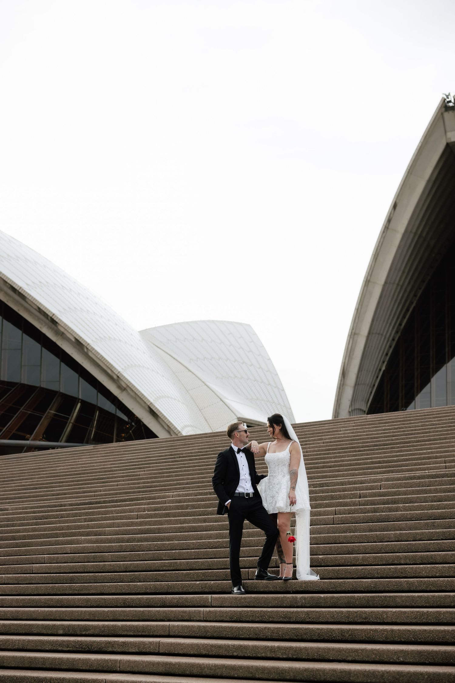 Bride and groom share a romantic moment on the grand steps of the Sydney Opera House after their Sydney CBD elopement.