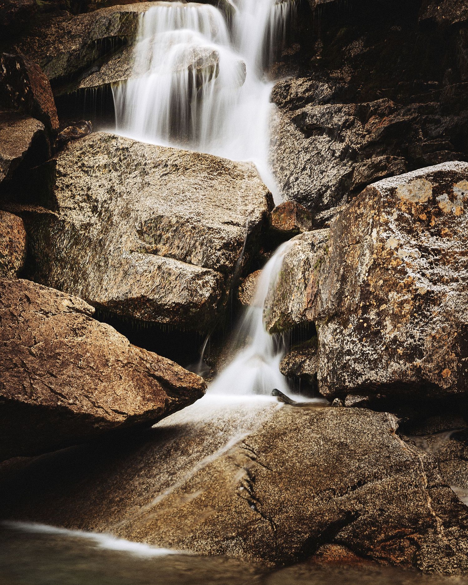 Close-up of a waterfall cascading over brown rocky formations with silky smooth water effect.
