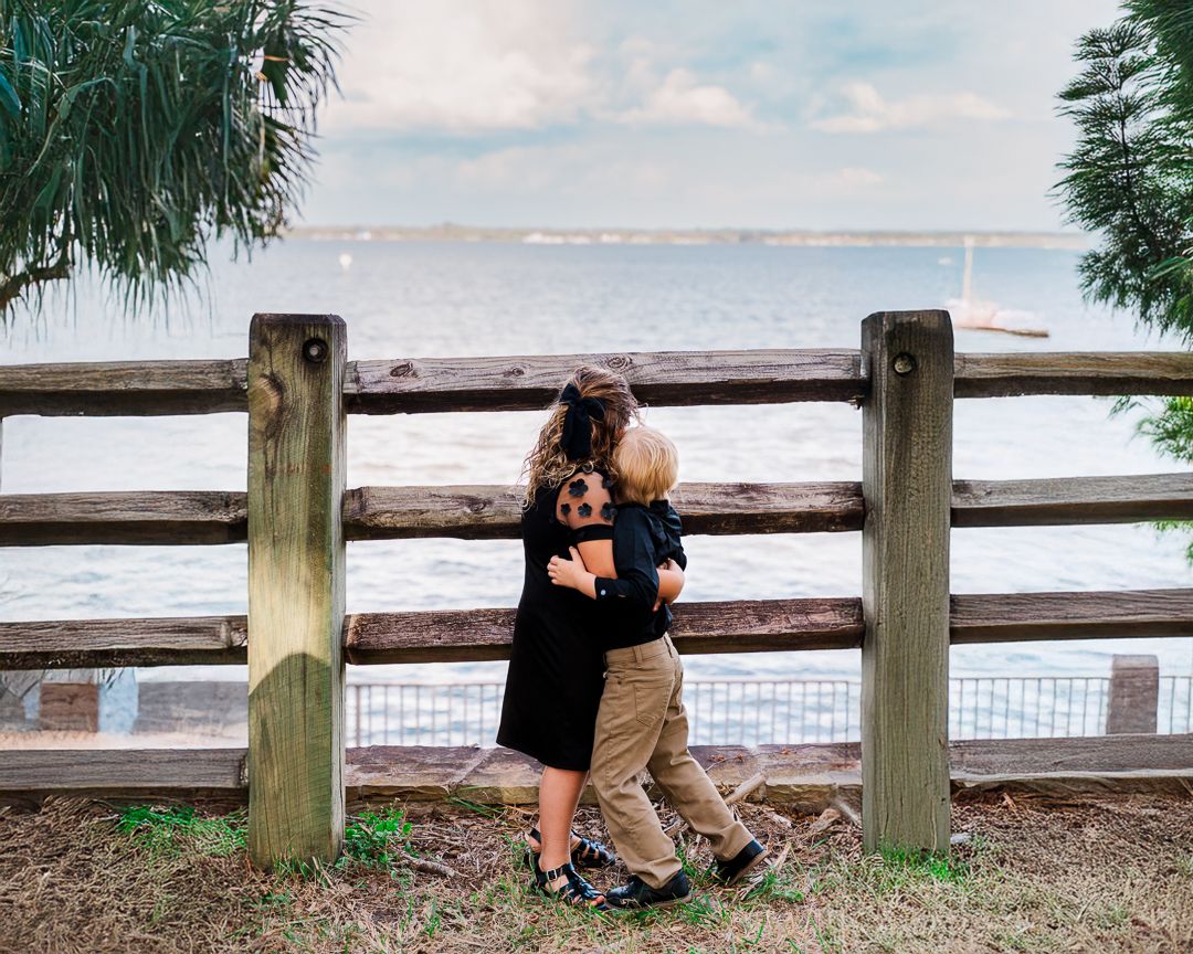 family session with sister and brother hugging while looking out at the water. Phillippe Park in Safety Harbor, Florida