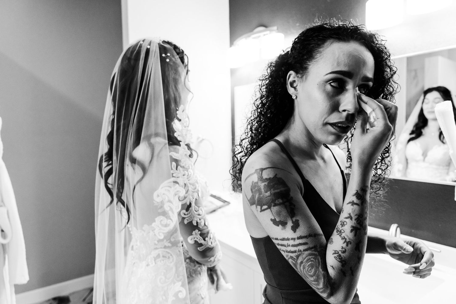 Black and white photo of bridal preparations with tattooed bridesmaids before a wedding ceremony.