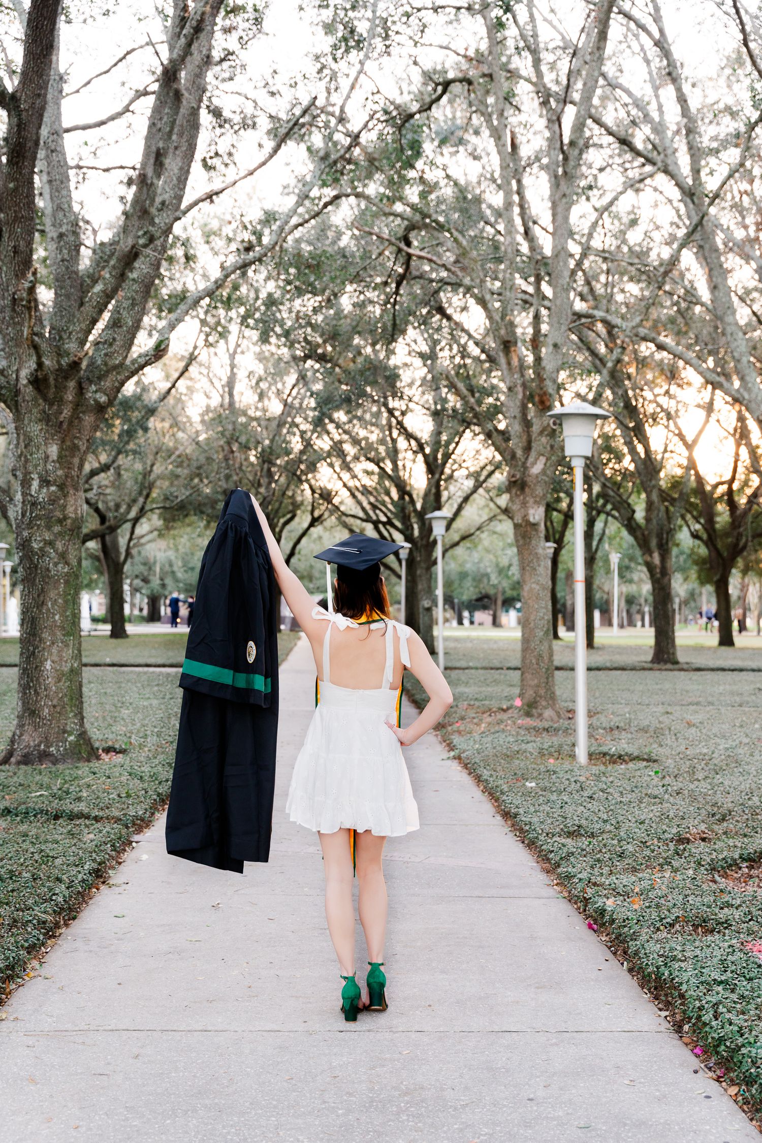 Walking away photo series showing graduation attire against a tree-lined pathway.