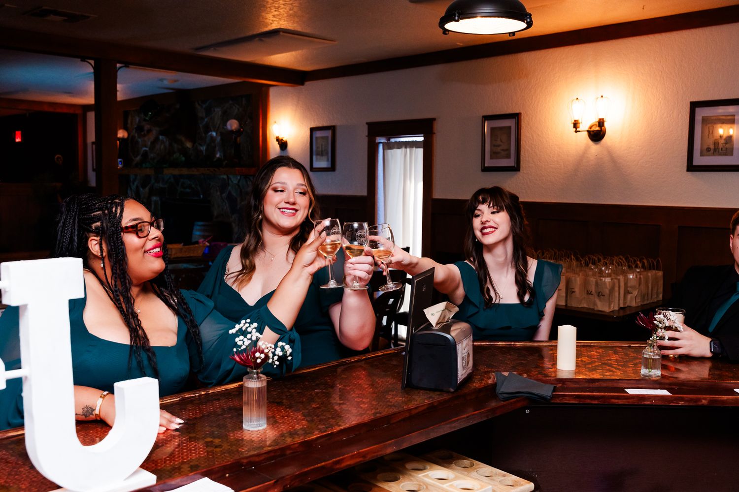 Friends toasting and enjoying drinks together at a cozy bar with warm lighting.