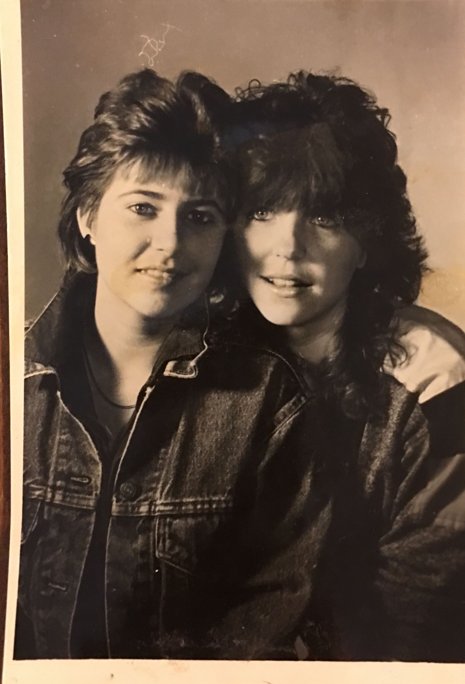 Sepia-toned retro portrait showing two friends in casual 80s style.