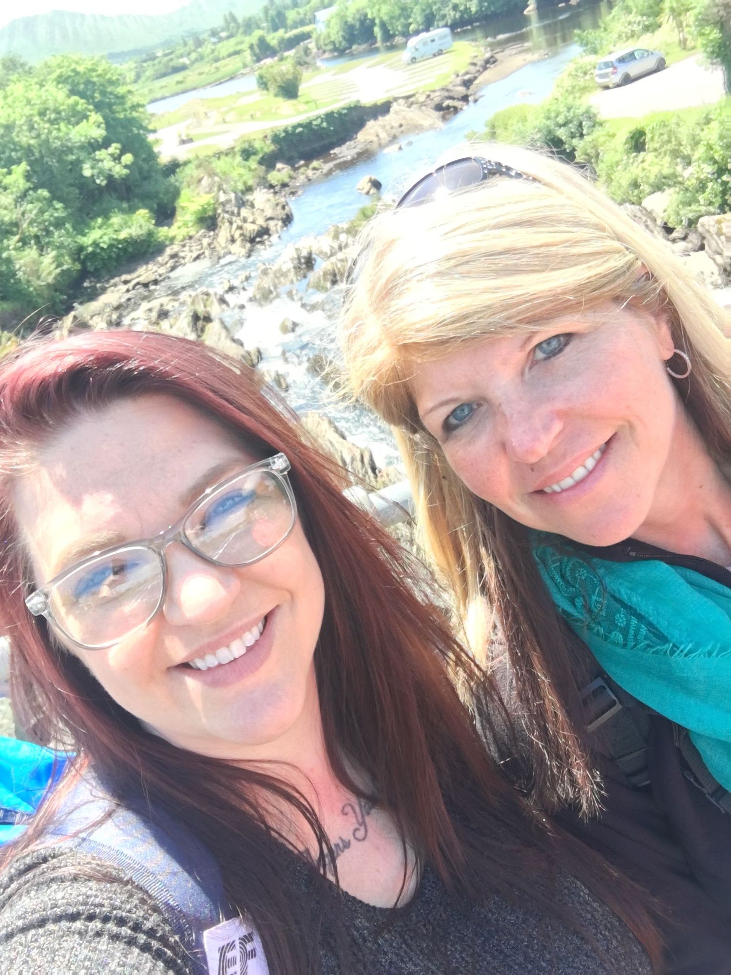Outdoor selfie taken at a scenic waterfall overlook on sunny day.