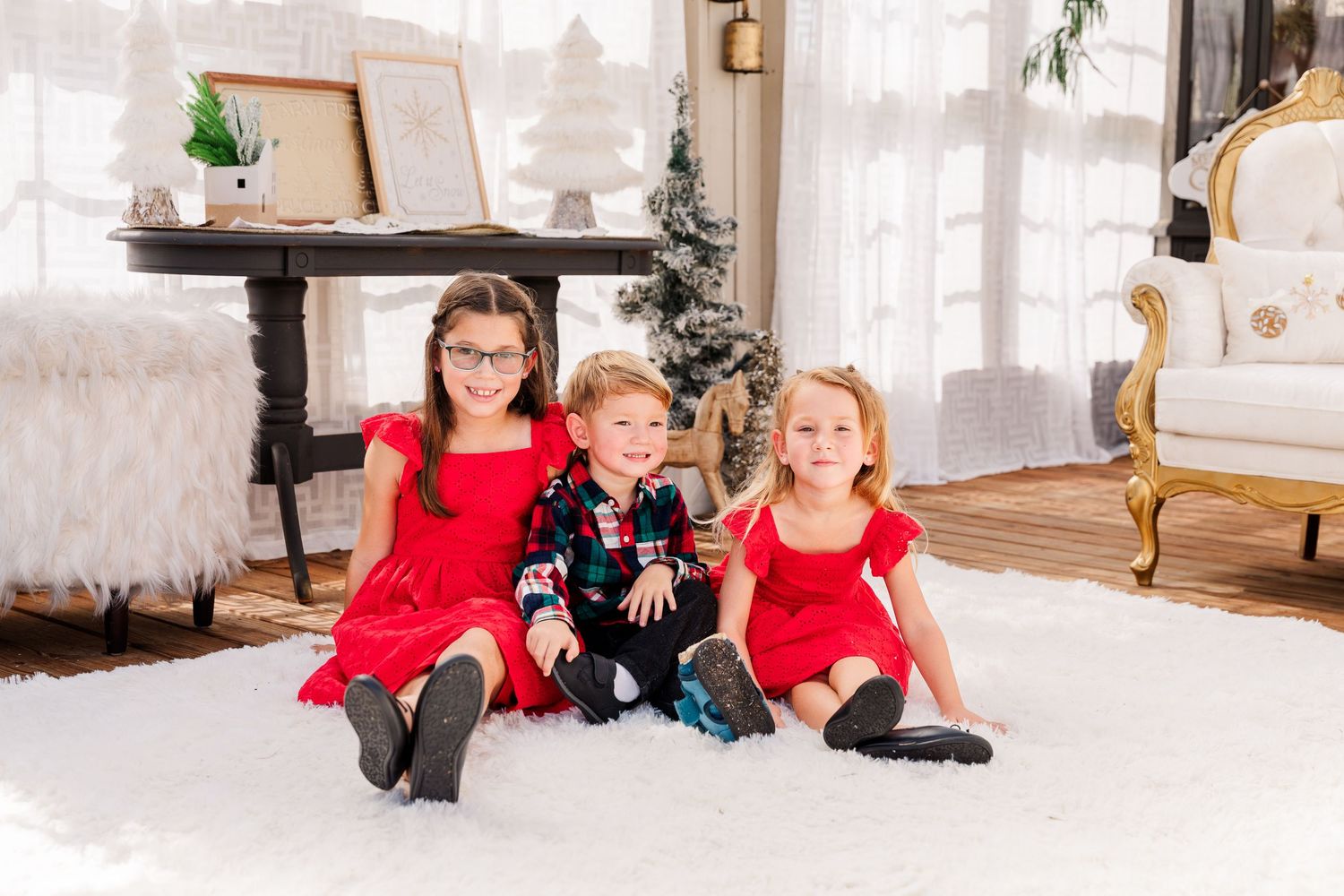 A family with matching red outfits sits together in a formal white room for holiday photos.