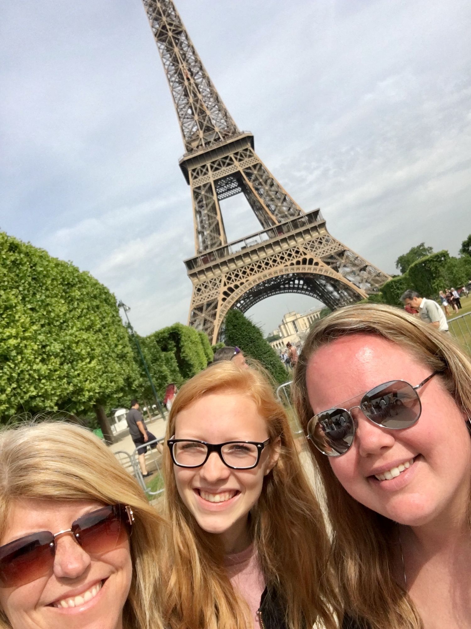 Tourist selfies with the iconic Eiffel Tower in Paris on a cloudy day.