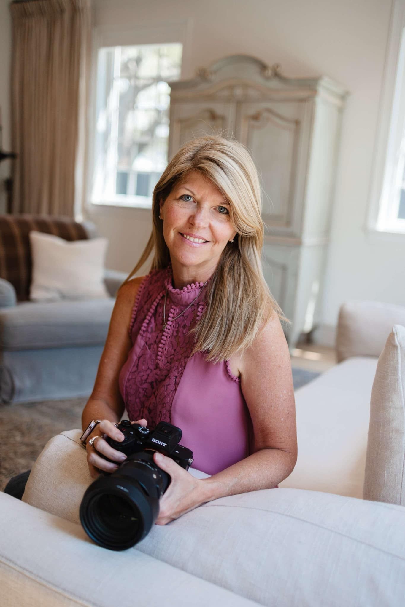 Professional photographer reviewing images on camera in an elegant white interior room.