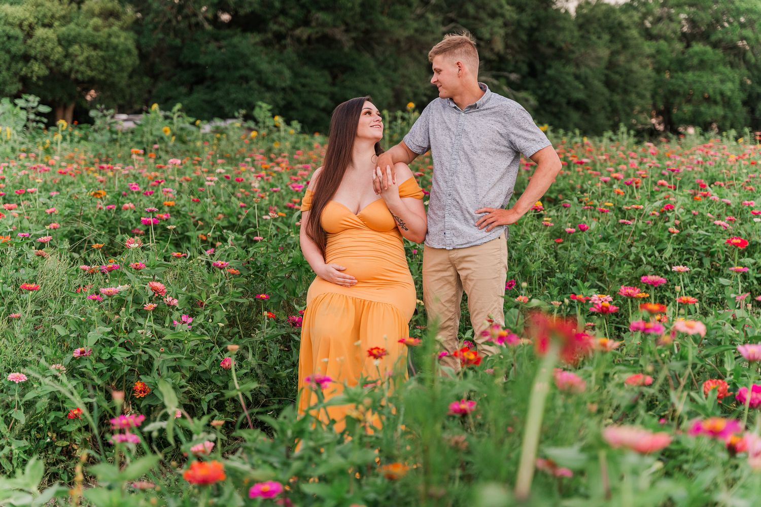 Couple enjoying a romantic moment together in a colorful wildflower garden filled with vibrant orange and red blooms.