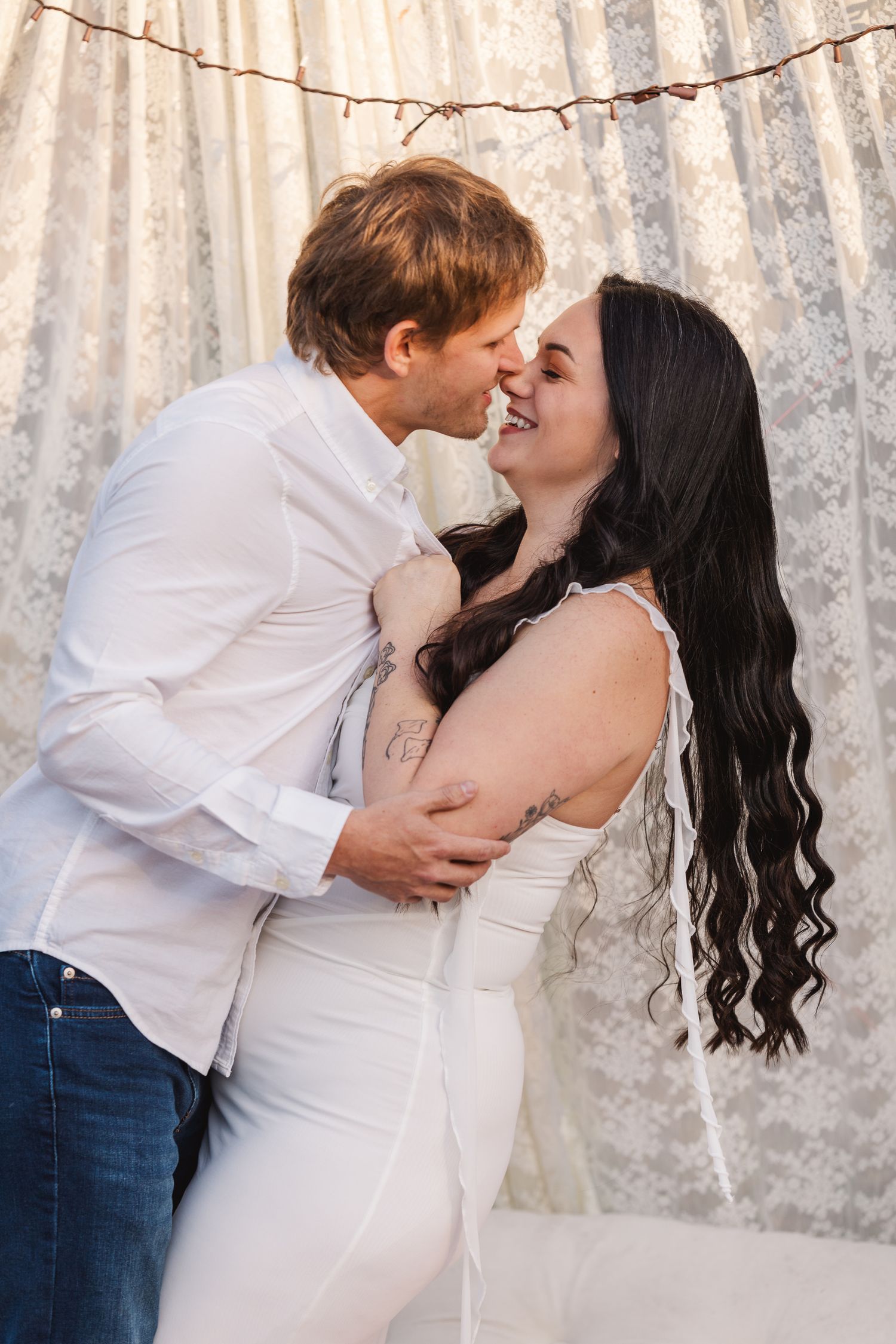 Romantic couple in white and denim share passionate kisses against a silver sequin backdrop in a photo series.
