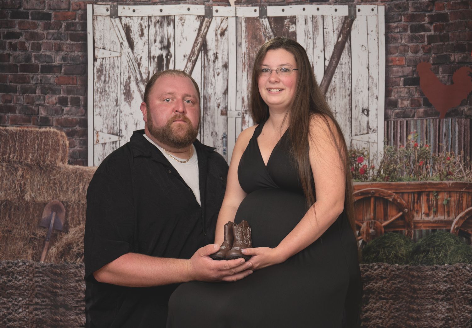 A couple in formal attire poses together against a rustic white barn door and brick wall backdrop.