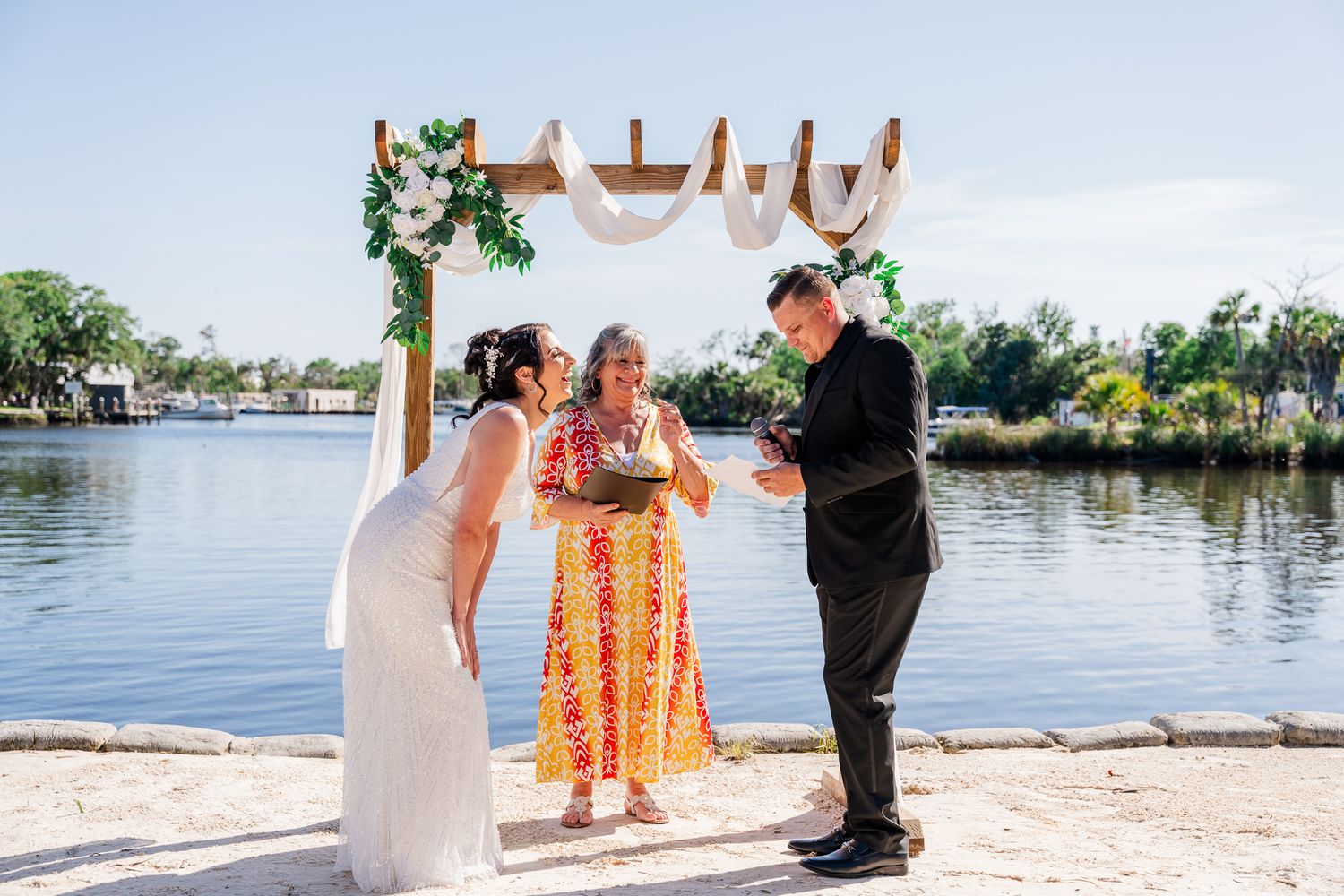 Beach ceremony setup with wooden arch and ocean backdrop.