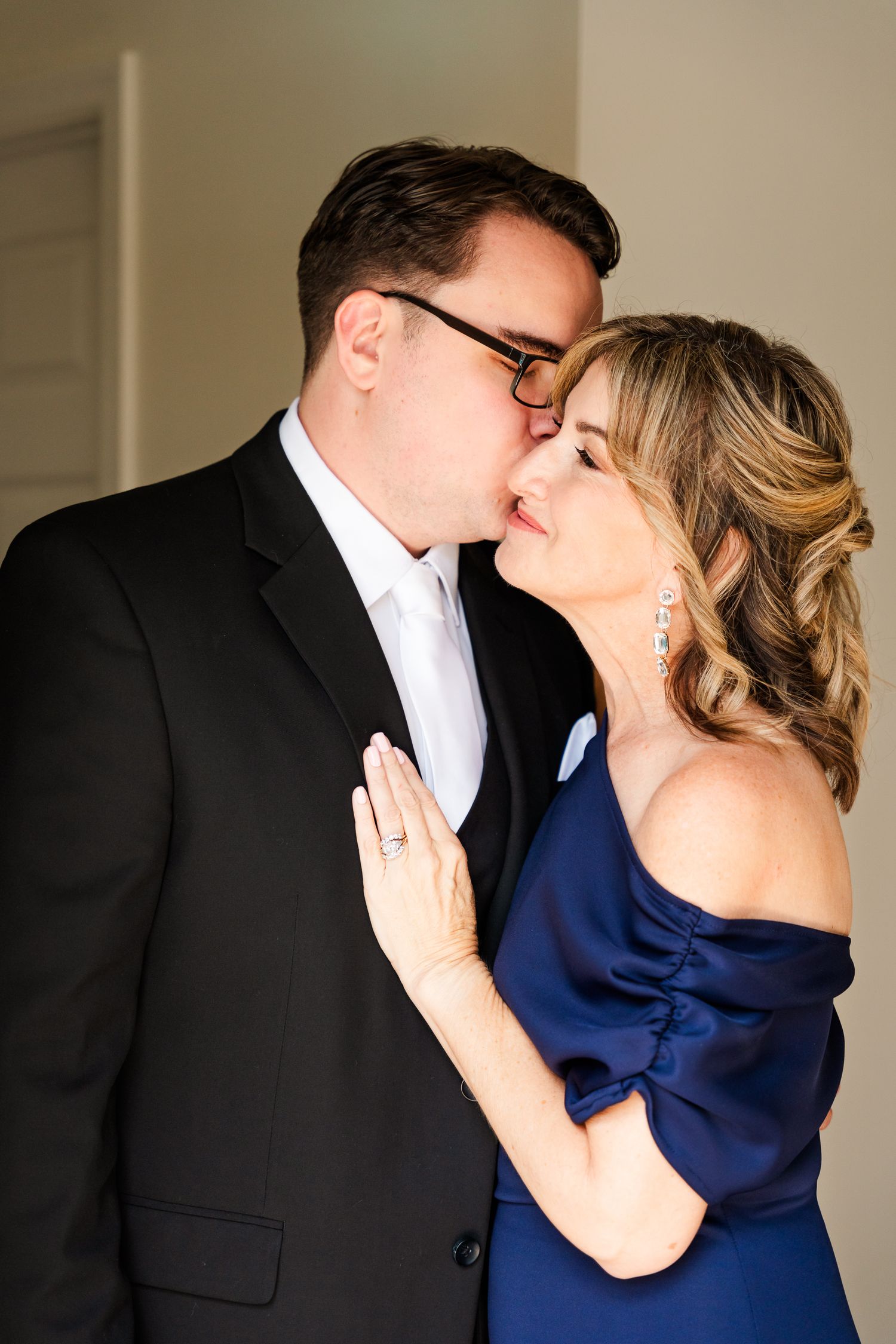 Romantic couple sharing multiple intimate kisses while dressed in formal black suit and elegant blue dress.