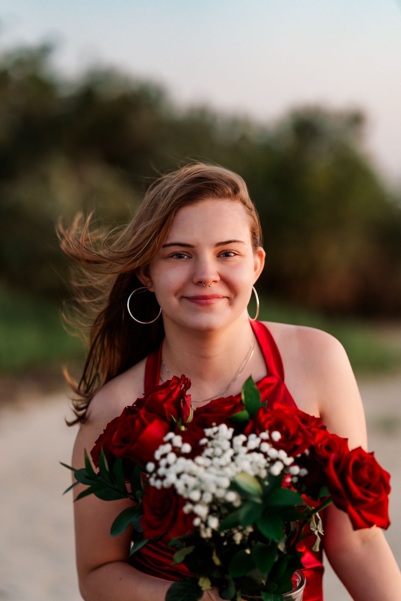 Portrait session with red roses and baby's breath flowers at golden hour.