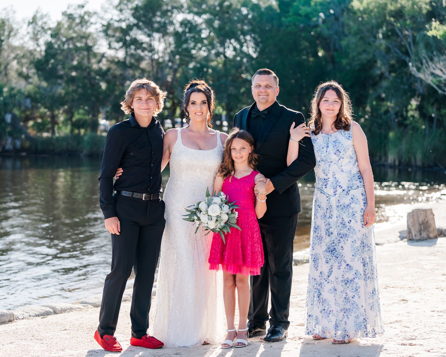 Group poses together on beach with water in background for special occasion photos.