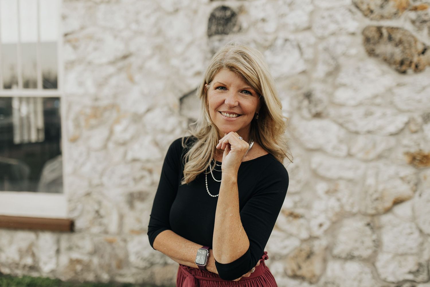 A cheerful outdoor portrait against a white stone wall.