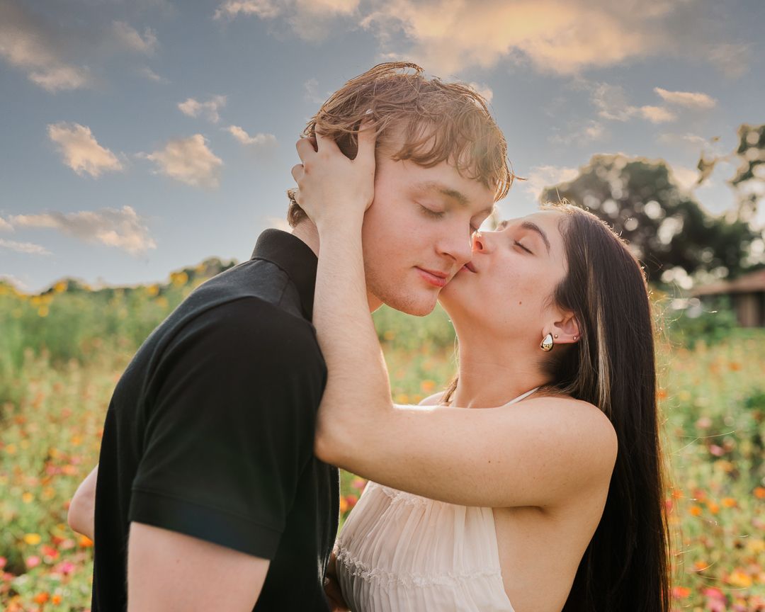 Romantic couple shares tender moments in a sunlit wildflower field at golden hour.