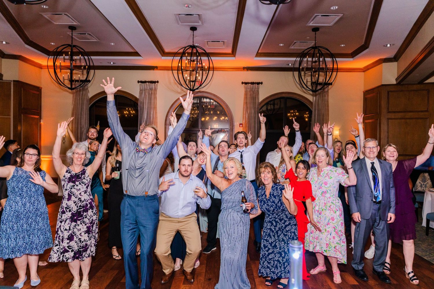 Wedding reception party with guests dancing under warm lighting.