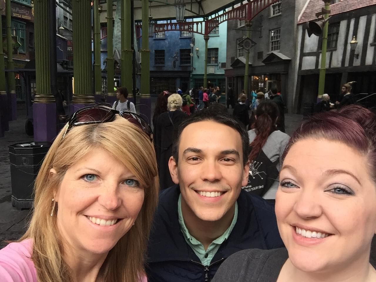 Group selfie taken at The Wizarding World of Harry Potter with themed architecture visible.