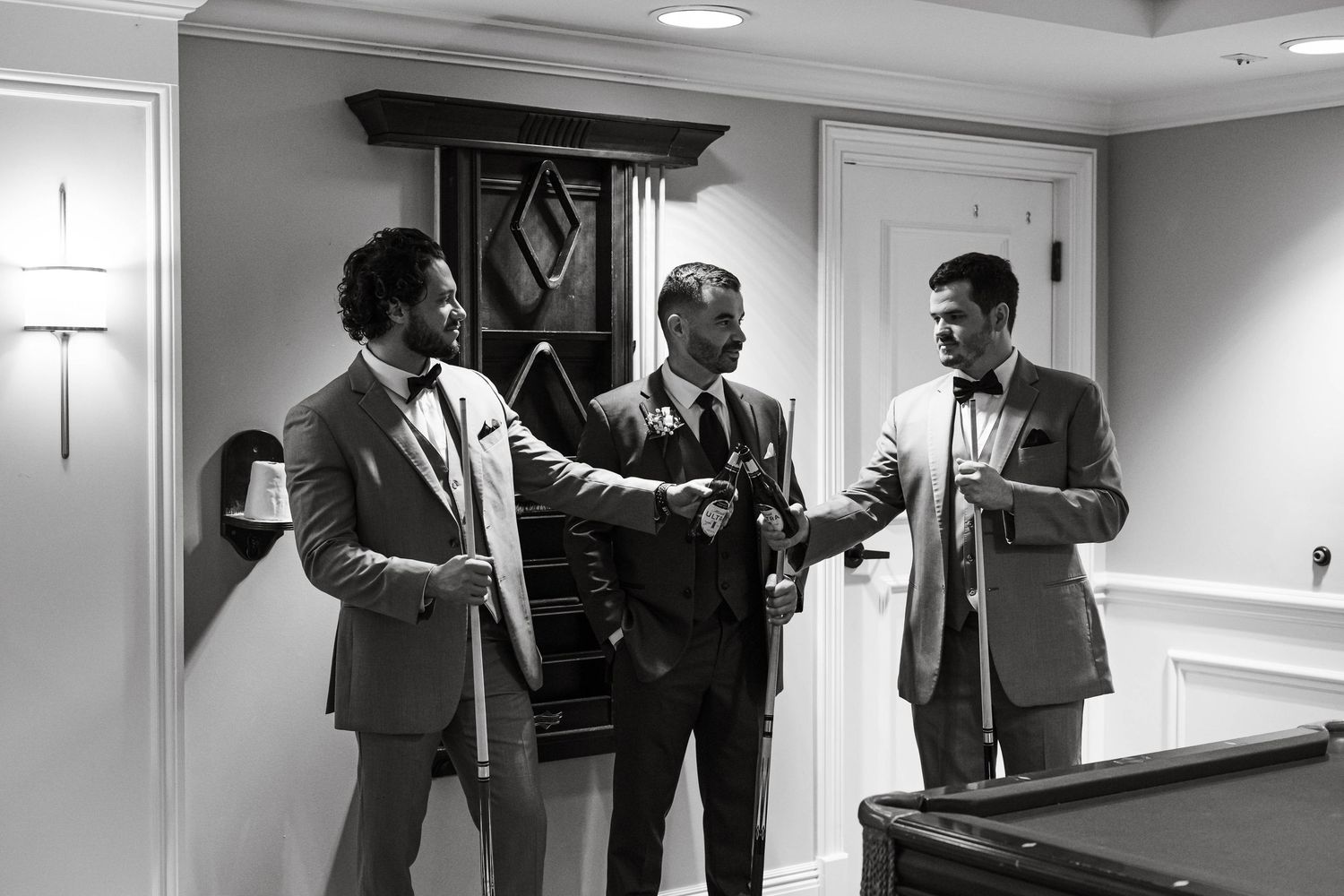 Black and white photos of groomsmen getting ready in hotel hallway.