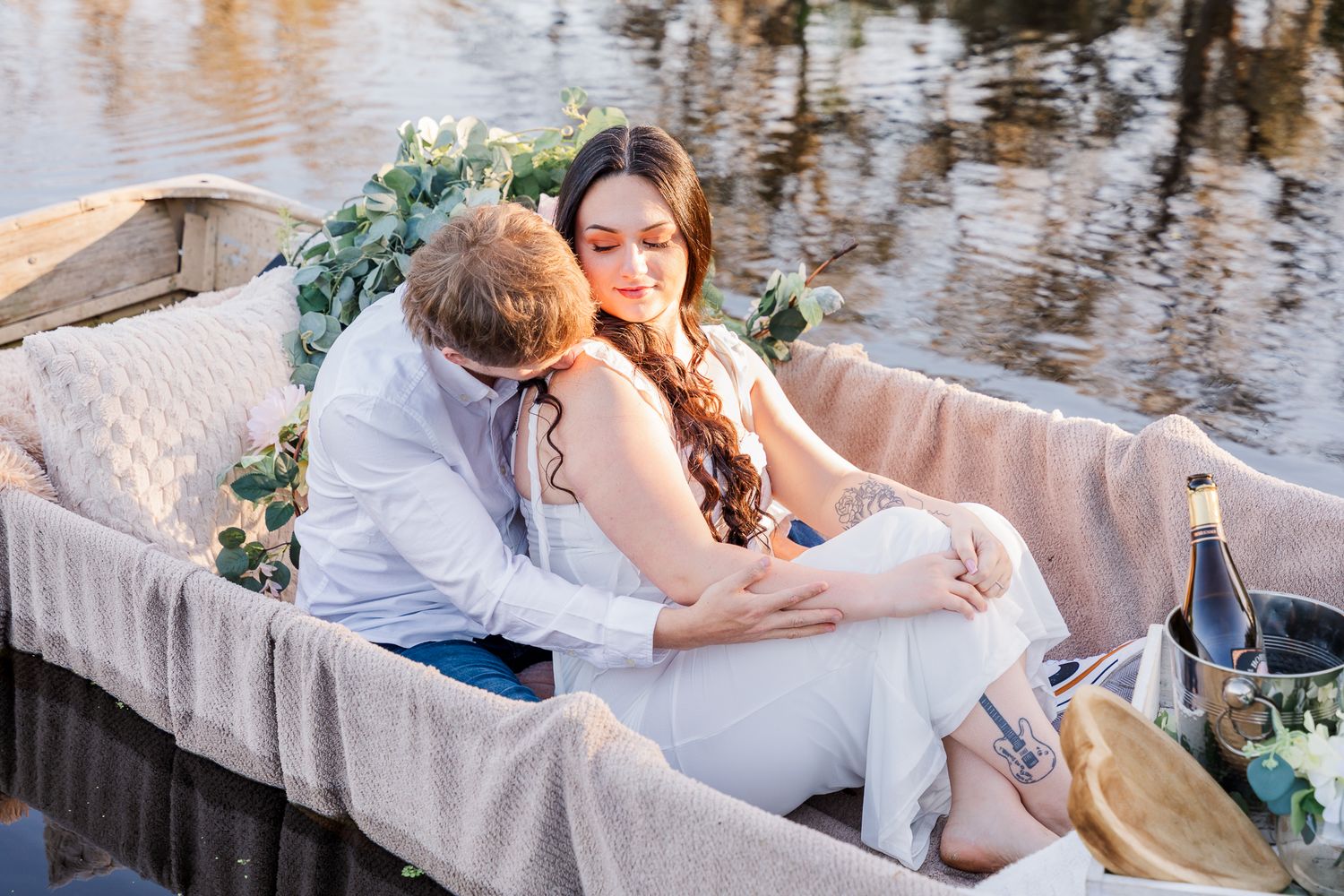 A romantic couple shares a tender moment by the water's edge during their outdoor wedding photoshoot.