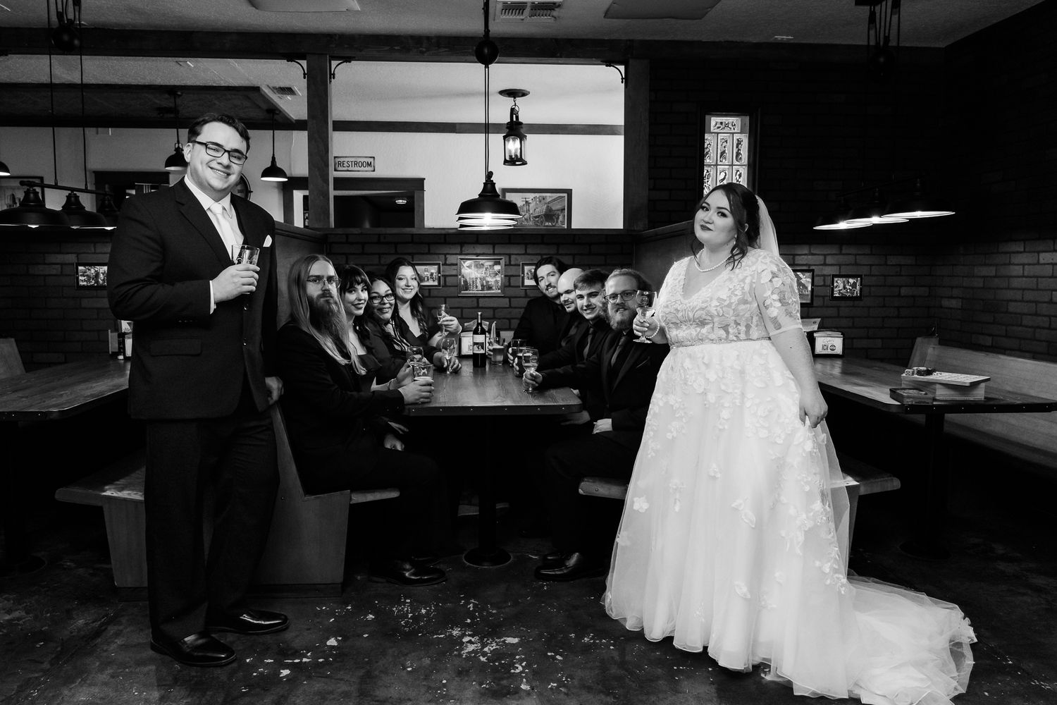 Black and white wedding reception photo showing celebration in a casual bar setting.