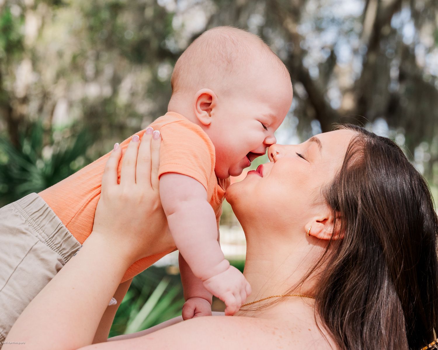 Parent lifting baby in air for playful bonding moment outdoors.