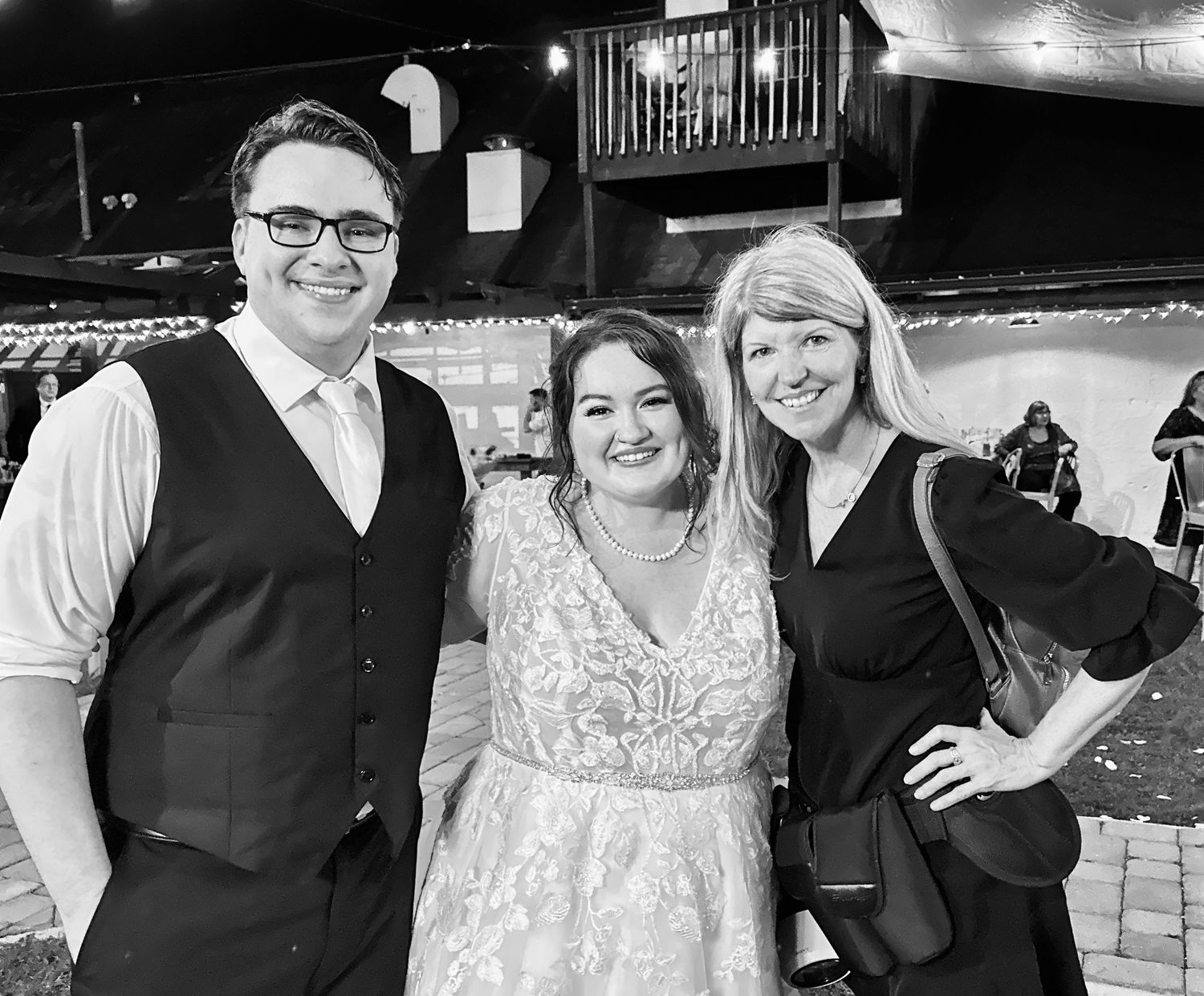 Kathy with her bride and group at their Wedding celebration in a rustic venue with festive mood lighting.