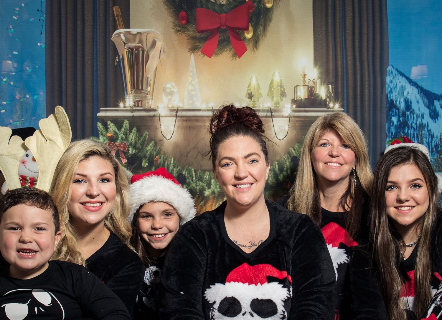 My family Holiday photo with Christmas decorations and group wearing festive Santa hats.