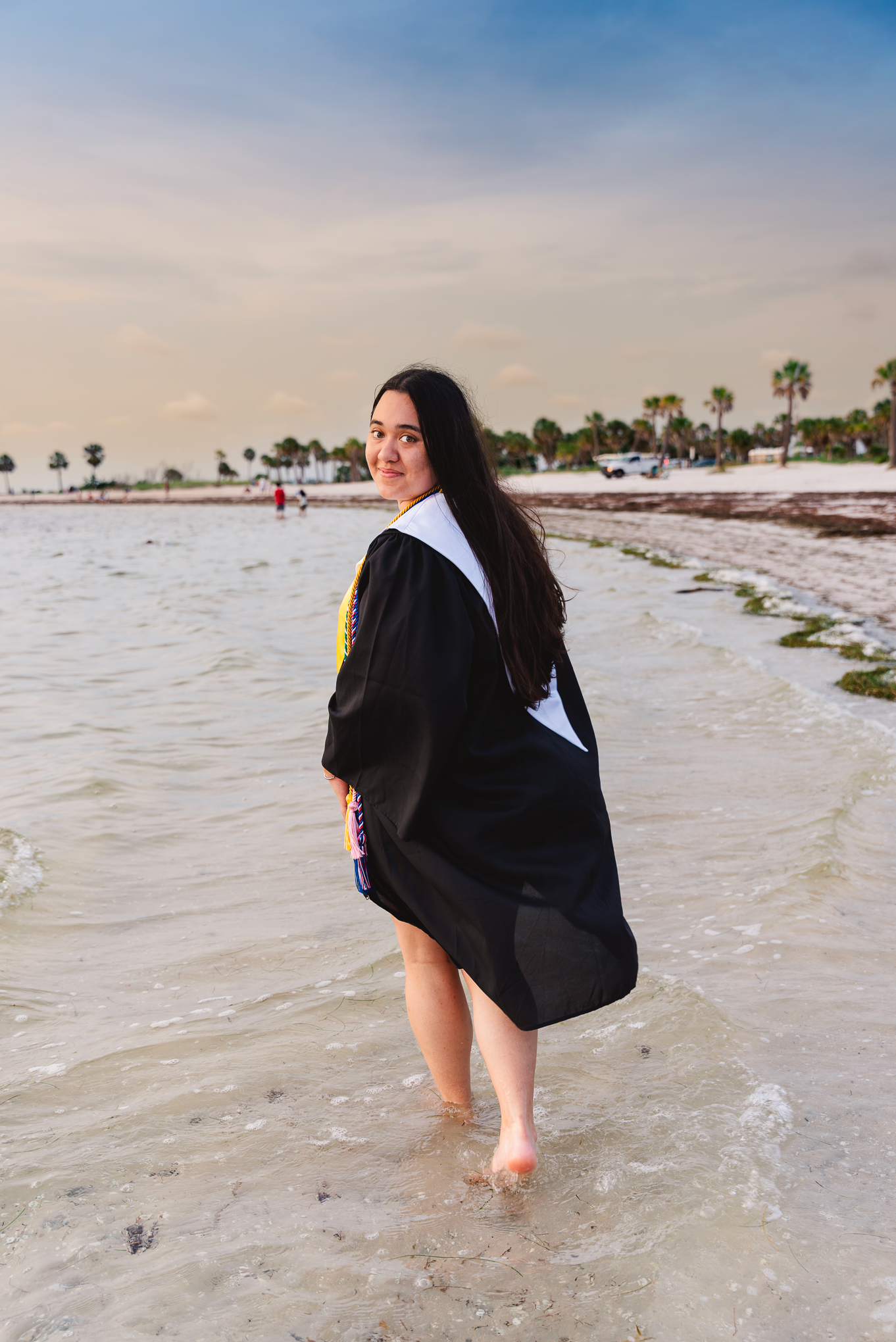 Person walking along a pristine white sand beach during golden hour.