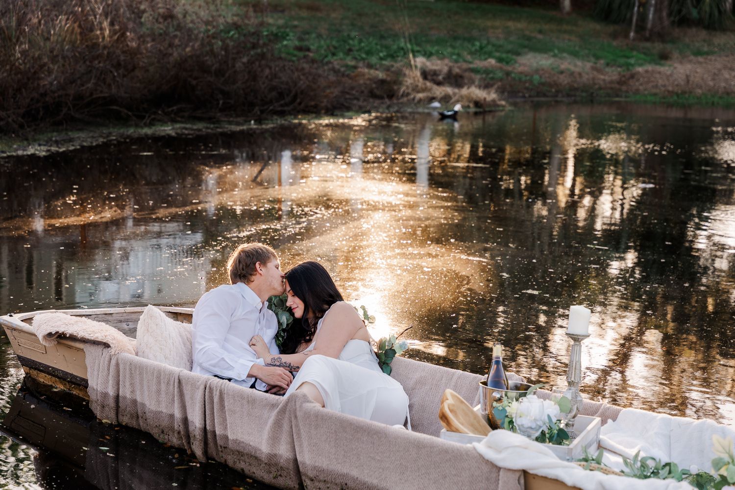 A romantic lake engagement session at The Gathering Table Venue, Plant City in a boat  during golden hour - sunset reflections on the water.