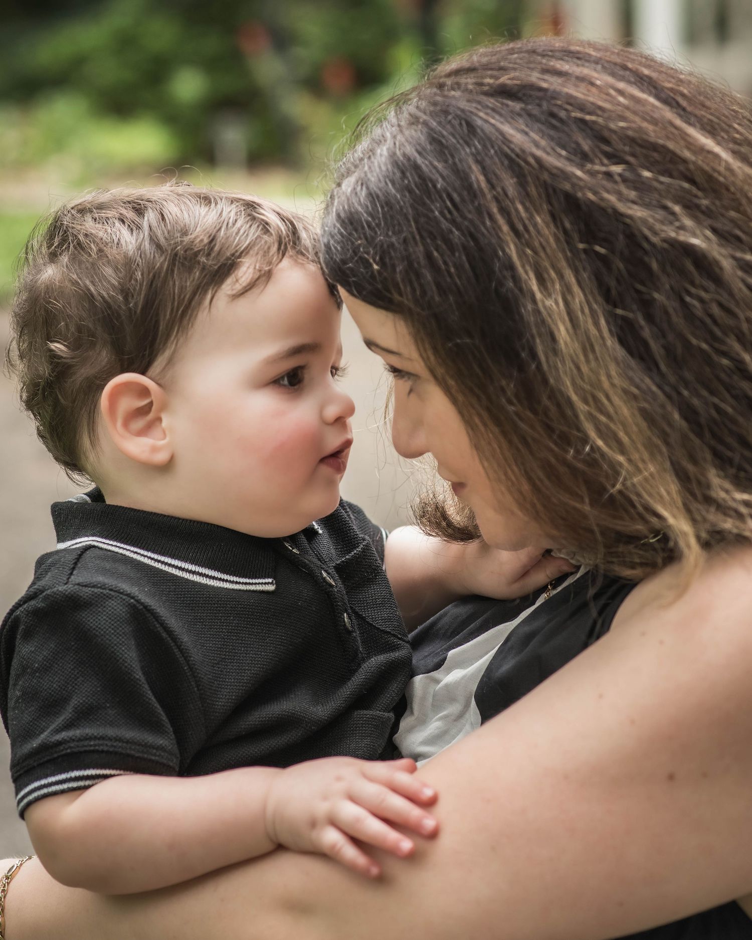 A mother tenderly holds her baby boy, their foreheads nearly touching in an intimate moment of bonding.
