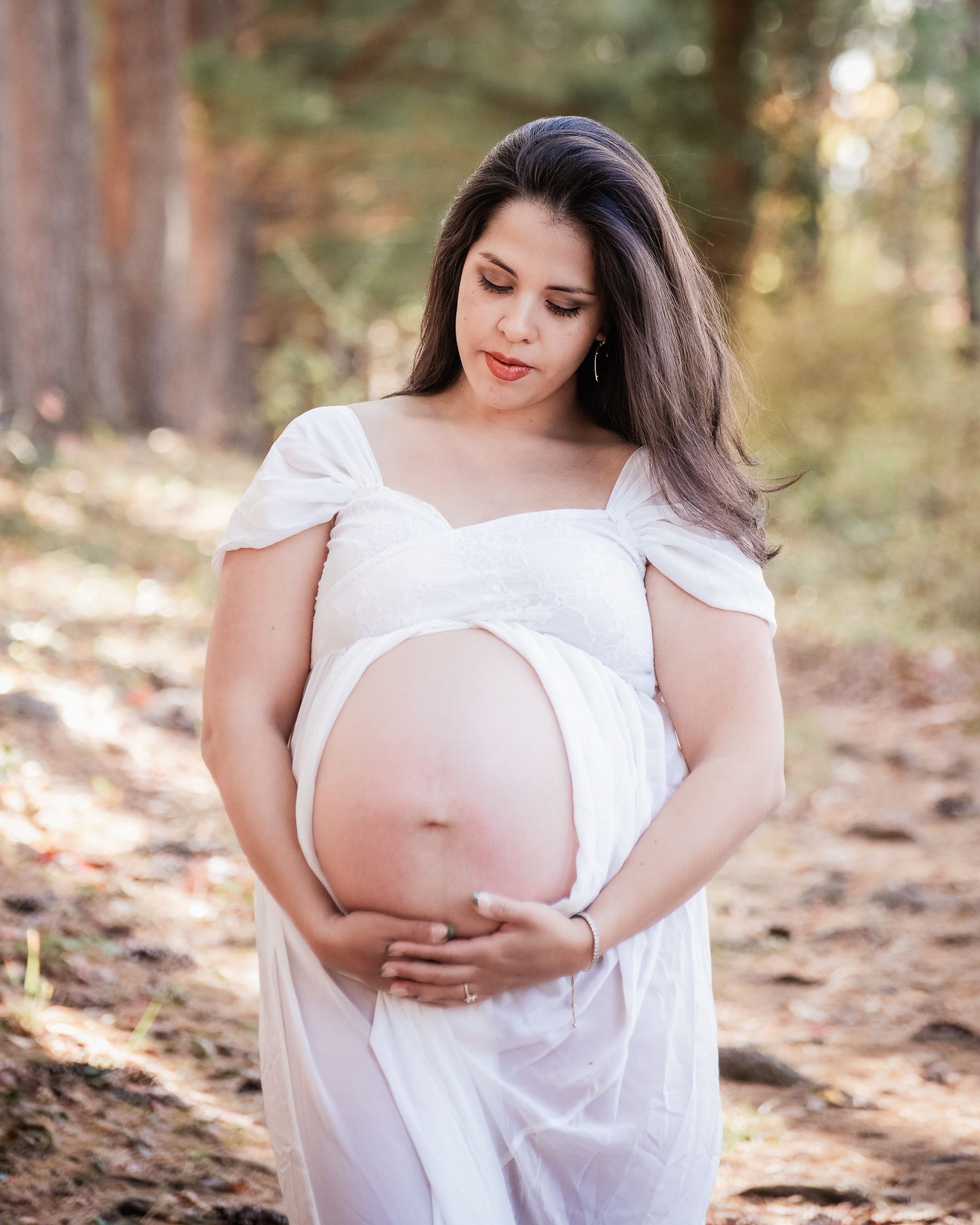 A series of maternity photos showing a woman in a white dress cradling her belly in a sunlit forest setting.