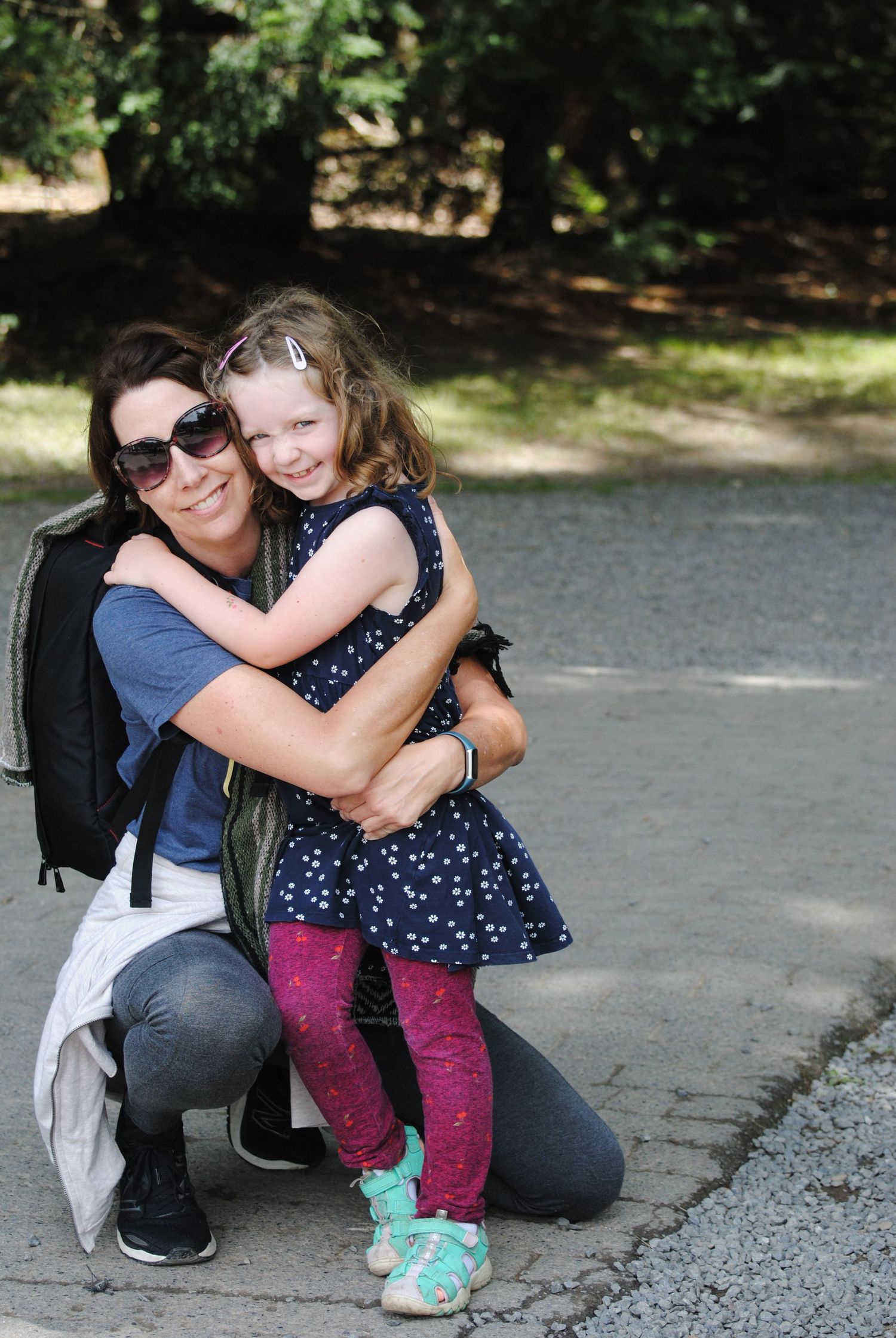 A sweet embrace shared between an adult and child in a polka dot dress and pink leggings outdoors.