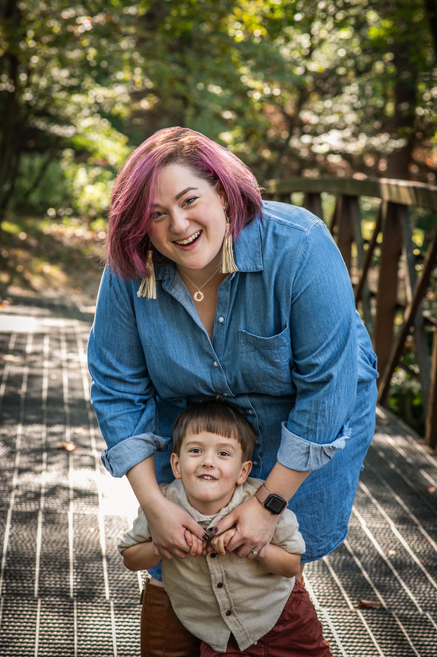 A joyful moment captured on a wooden bridge in nature as parent and child share laughter and hugs together.