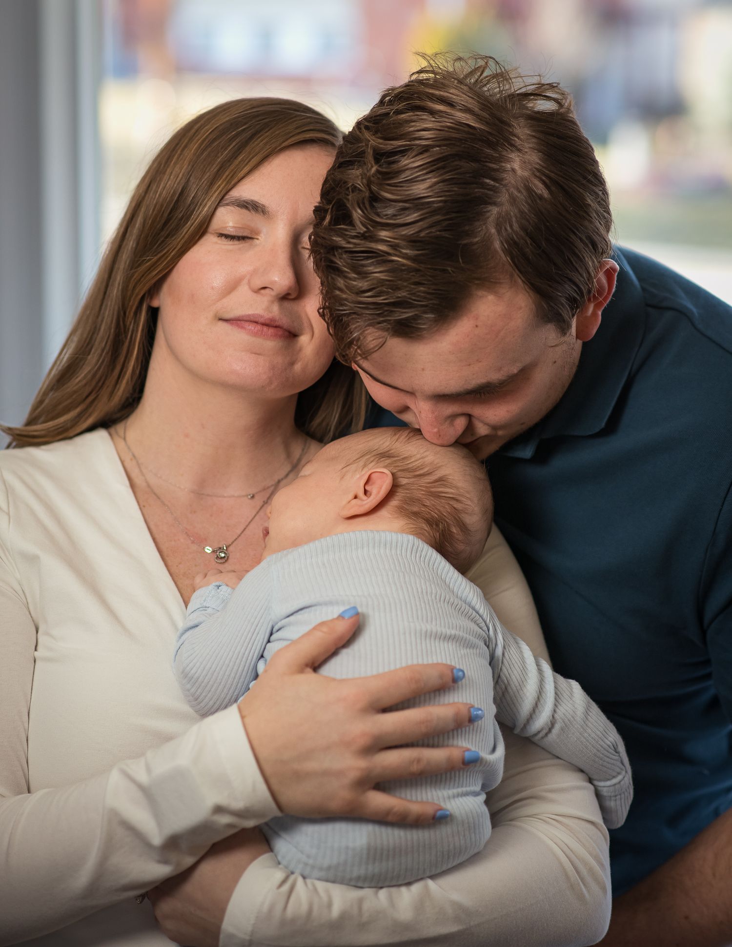Parents lovingly embrace their newborn baby together in an intimate family moment.