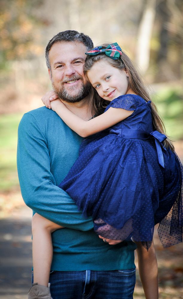 Parent and child share tender moment during portrait session, with child wearing navy blue dress.
