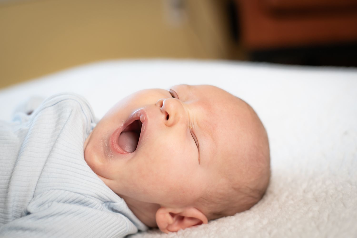 A sleeping baby lies on white bedding in a peaceful slumber.