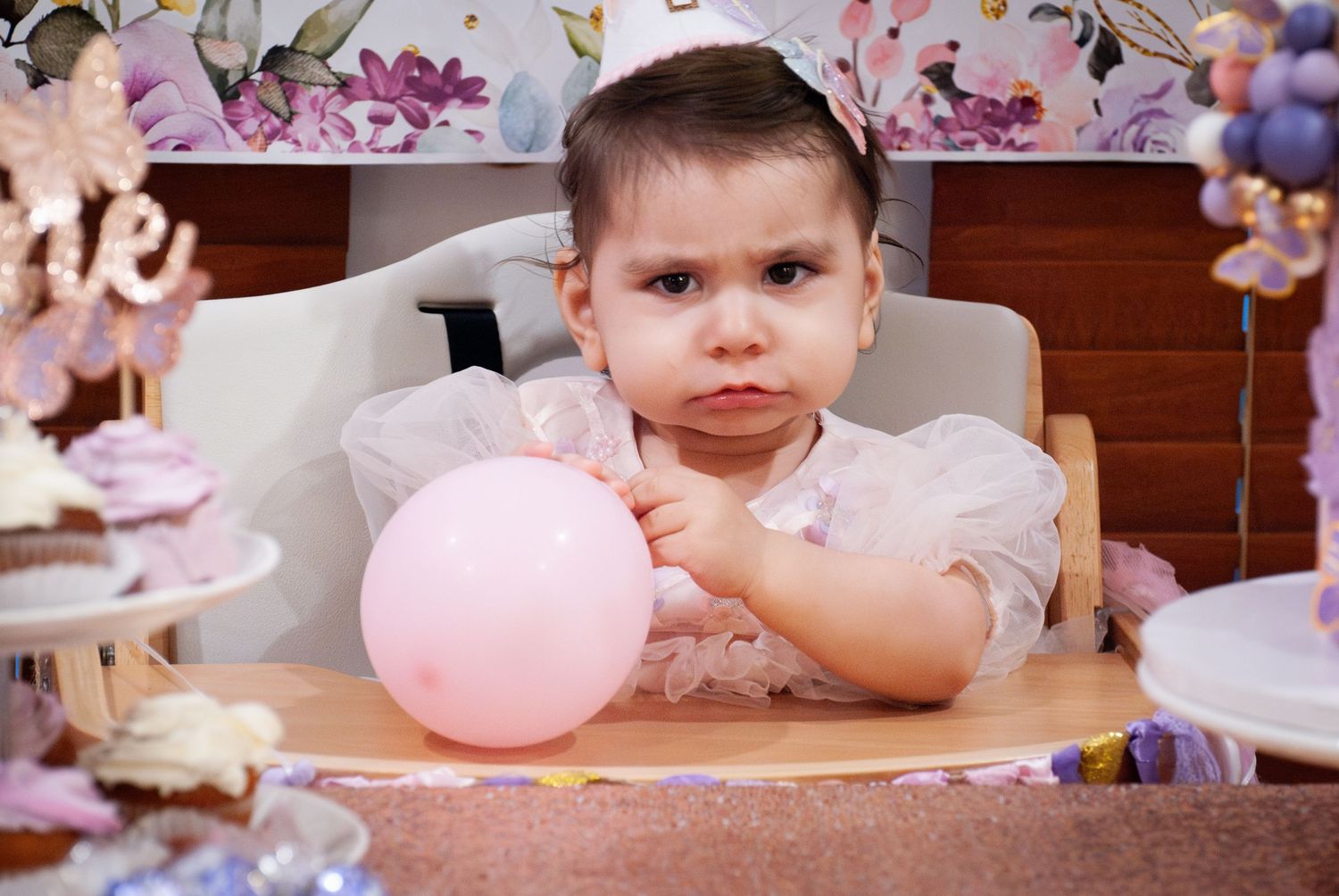 A pink balloon being blown up at a birthday party celebration with decorations in the background.