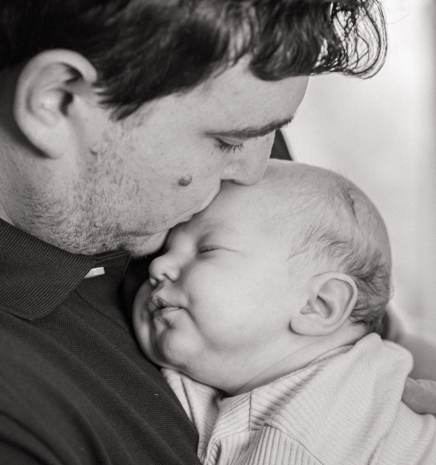 A tender black and white photo series showing close-up intimate moments between a parent and baby.
