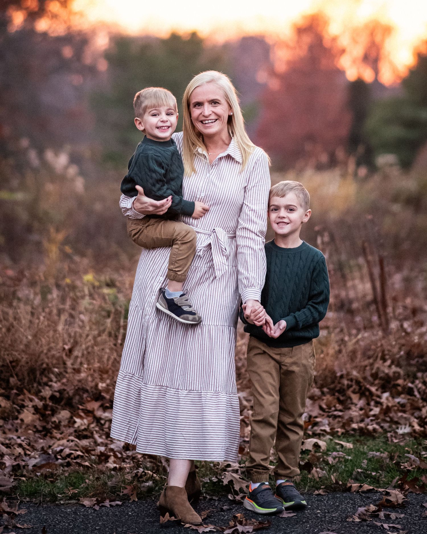 Family enjoying a sunset photoshoot together in a rustic outdoor setting with golden autumn light.