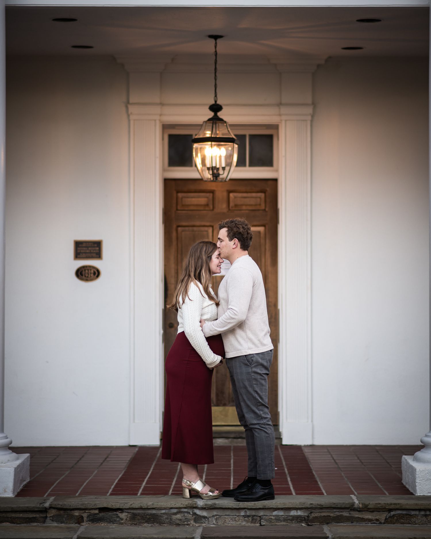 A romantic couple embraces in a series of four progressive photos along an elegant hallway with pendant lighting.