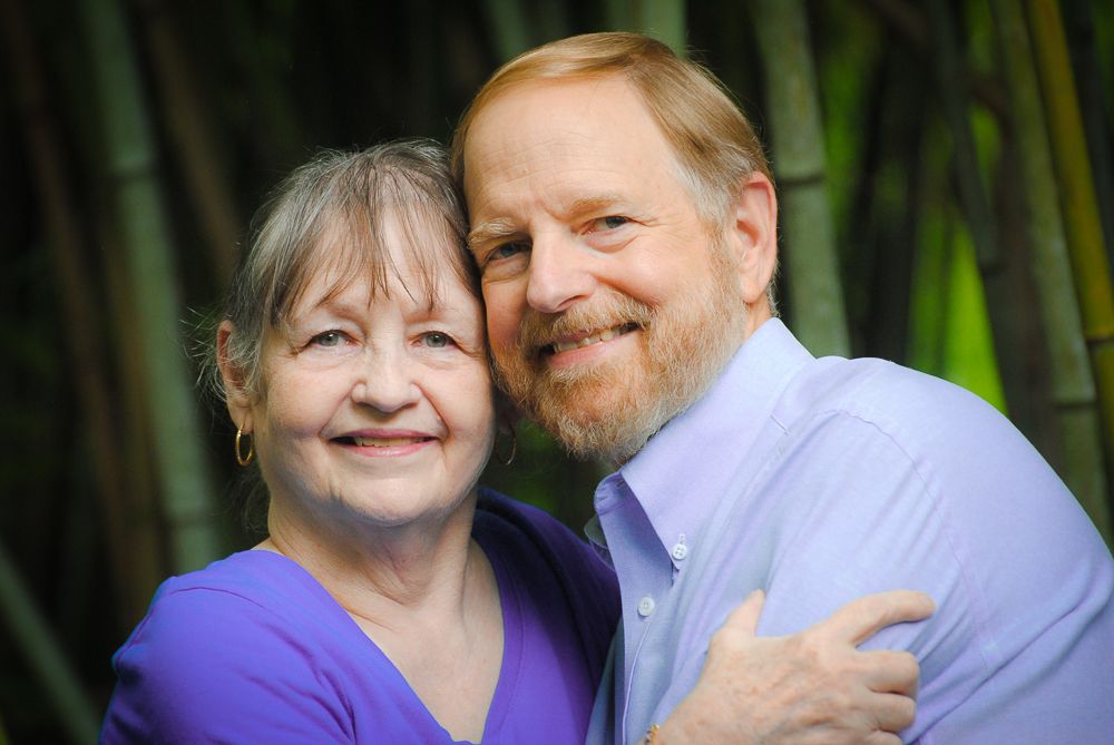 Happy couple embracing and laughing together in a casual outdoor setting.
