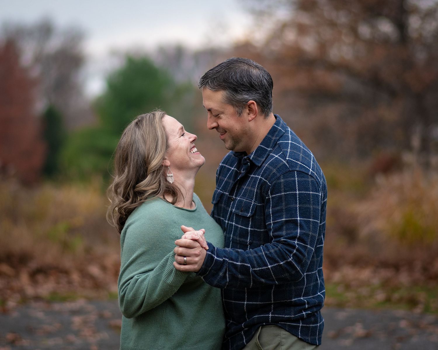 A couple shares romantic moments together outdoors during an autumn engagement photo session.