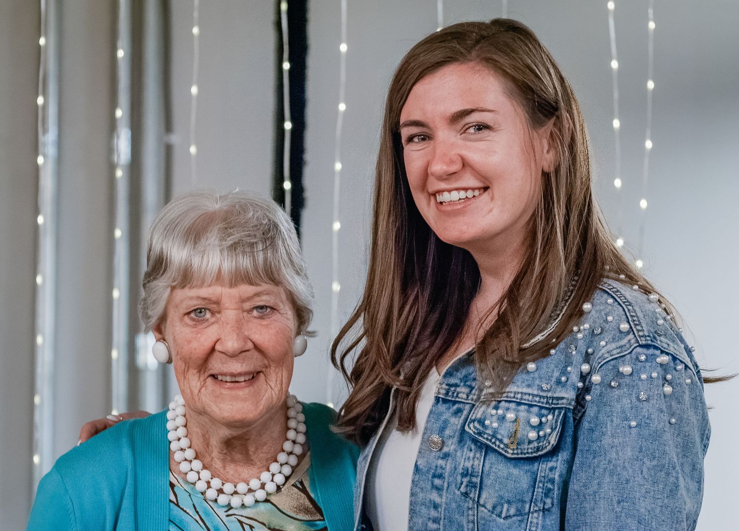 Two generations share a warm moment together against a backdrop of twinkling lights.