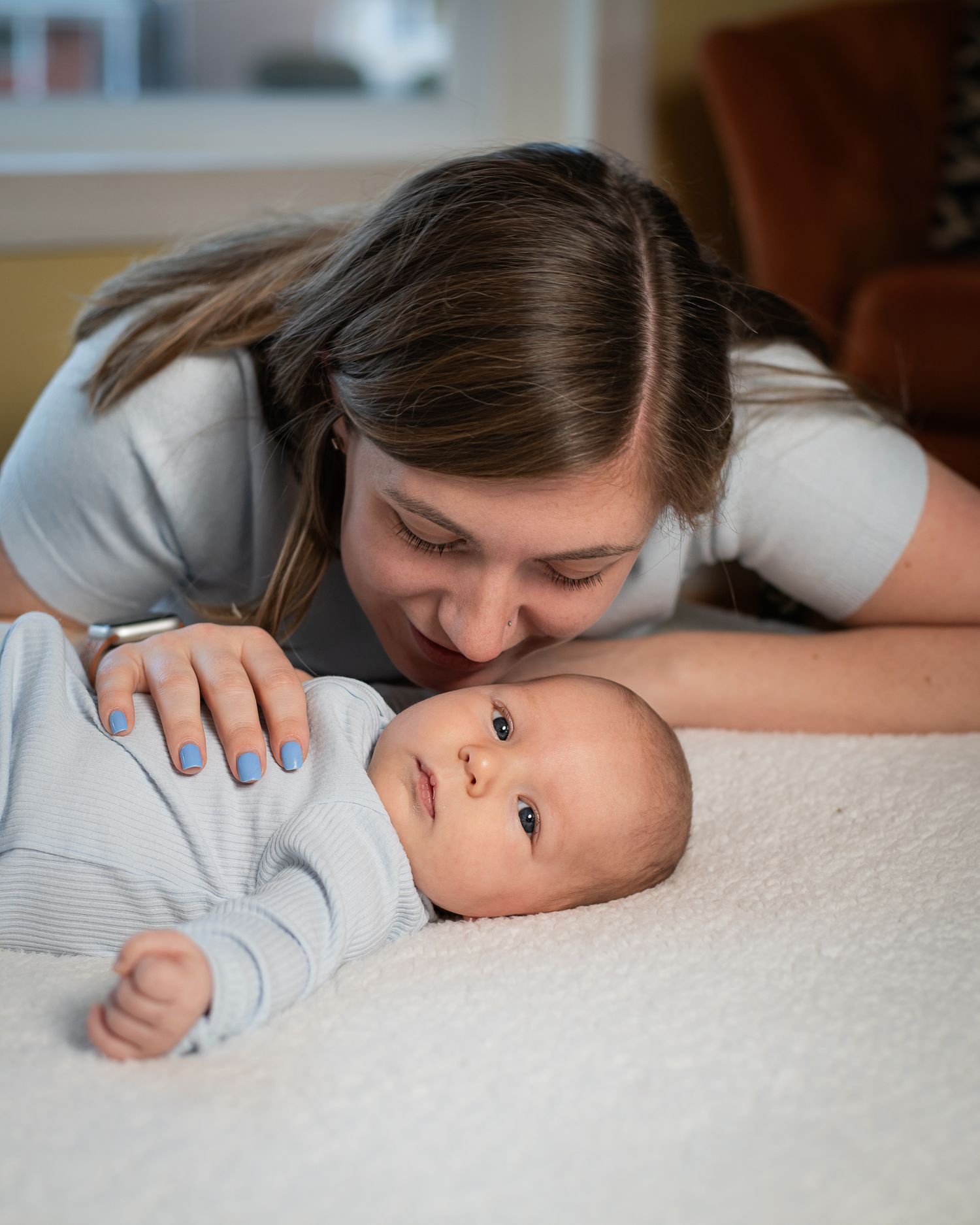 A tender moment between parent and baby lying on white bedding as they share a close intimate connection.