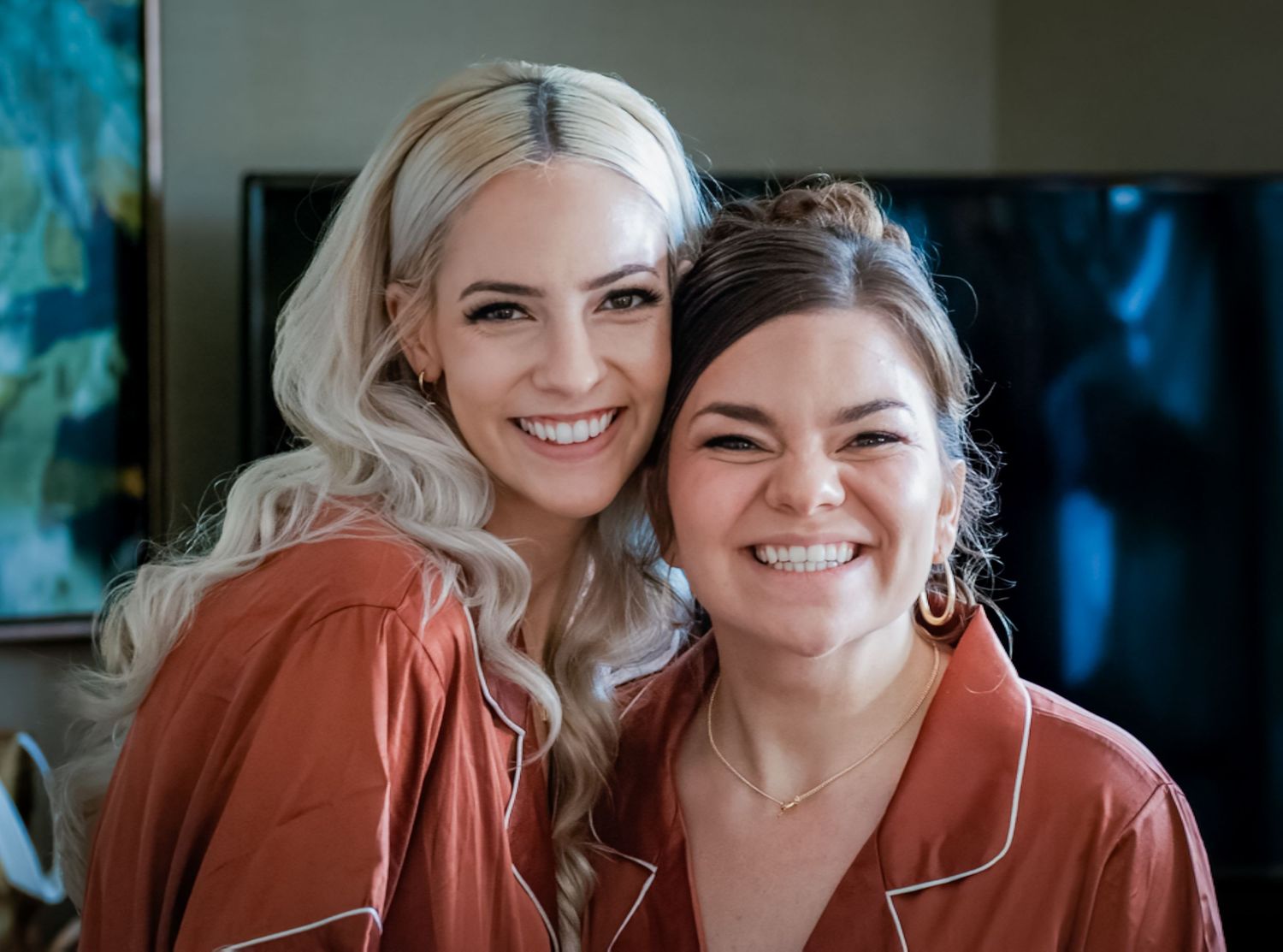 Two people smile warmly while posing together in matching outfits.