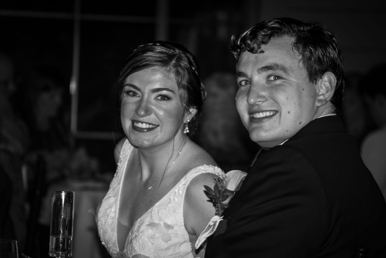 A black and white photo of a bride and groom smiling together during their wedding reception.