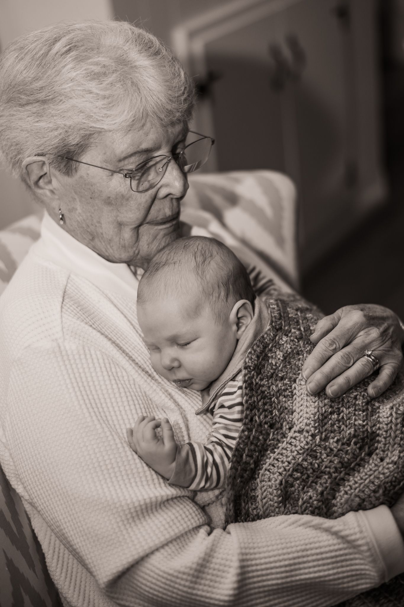 A tender black and white photo series showing a grandmother cradling and bonding with a sleeping baby.