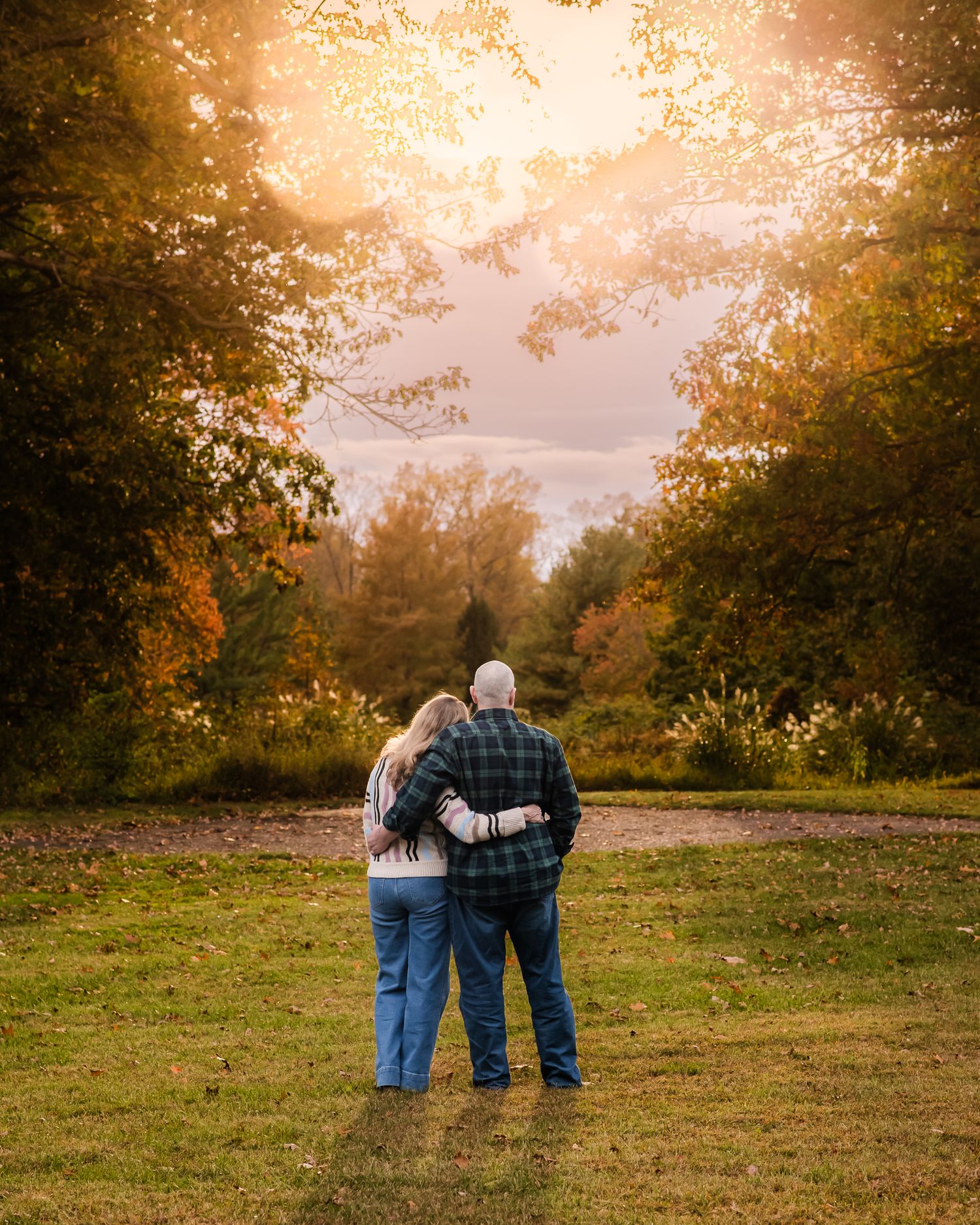 Couple embracing at sunset in autumn forest clearing with golden foliage and warm light.