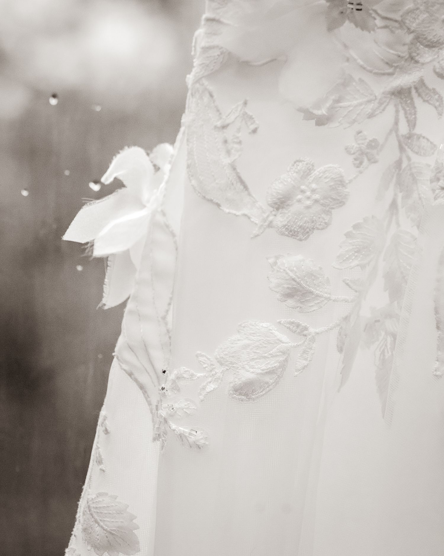 Close-up of an elegant white wedding dress featuring intricate floral lace appliqués and delicate embroidery details.